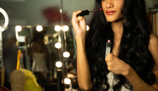 Demi-corps handicapé personne sans doigts pouce main de jeune femme adulte à l'aide d'un pinceau cosmétique rouge à lèvres au bureau miroir de maquillage Sourire féminin joyeux en robe de soirée blanche robe de bal cheveux longs