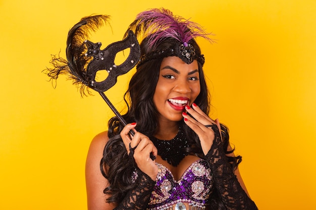 Photo demi-corps horizontal tourné d'une belle femme brésilienne noire en vêtements de carnaval tenant un masque de carnaval wow incroyable