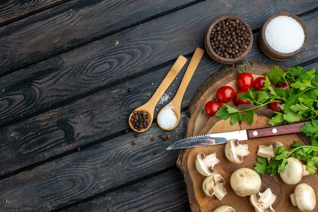 Demi-coup de champignons frais et d'épices de tomates au couteau sur une serviette en bois sur fond noir