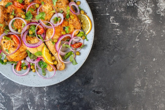 Demi-coup de délicieux dîner plat de poulet frit avec diverses épices et aliments sur le côté droit sur fond de couleur sombre gros plan