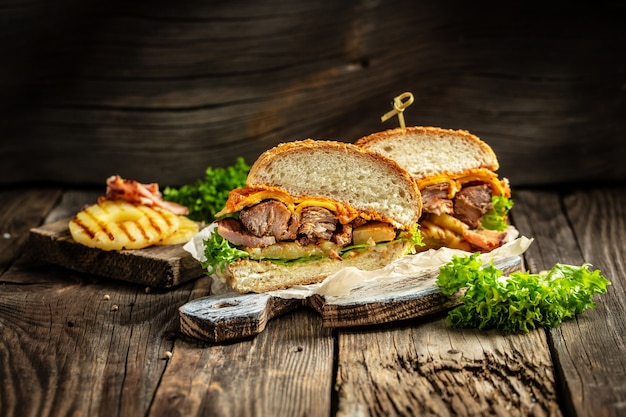 Un demi-hamburgers avec viande de bœuf grillée, légumes, sauce sur une surface en bois rustique