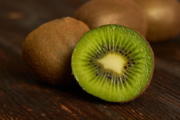 Demi kiwi mûr et kiwi entier isolé sur fond de bois