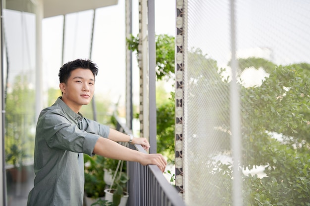 Demi-longueur de jeune bel homme debout sur un balcon extérieur,