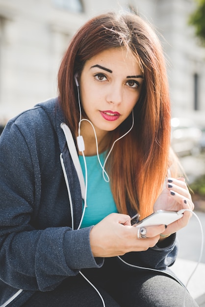 Demi-longueur de la jeune femme caucasienne beau cheveux roux écoute la musique