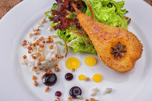 Une demi-poire caramélisée avec salade et gouttes de garniture