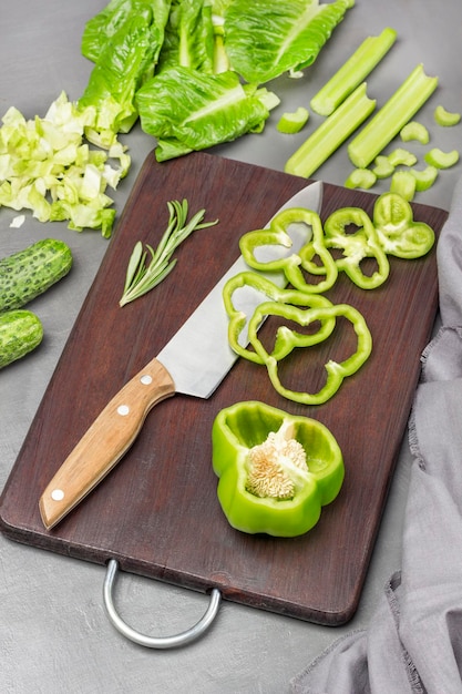 Un demi-poivron vert haché couteau de cuisine sur une planche à découper