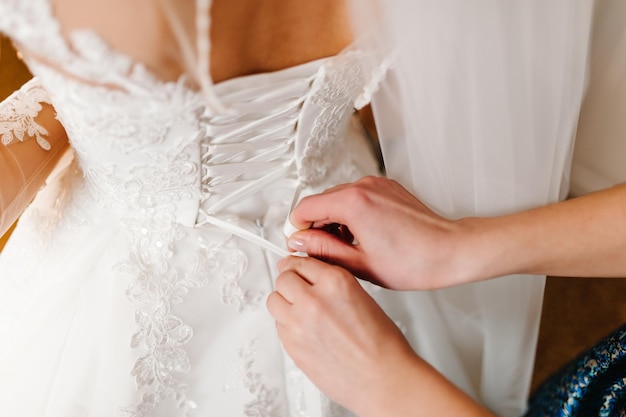 Demoiselle d'honneur aidant la mariée à attacher le corset et à obtenir sa robe préparant la mariée le matin pour le jour du mariage