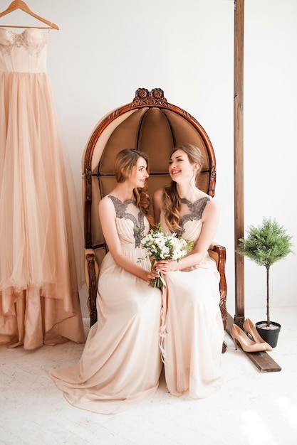 Demoiselle d'honneur avec un bouquet de mariage assis sur une chaise vintage