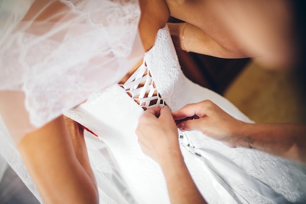 Demoiselle d'honneur nouant un arc sur une robe de mariée