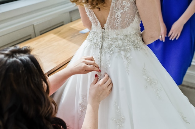 Les demoiselles d&#39;honneur aident la mariée à porter une robe de mariée