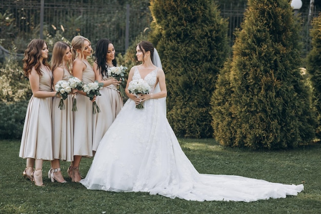 Les demoiselles d'honneur en robes pastel se tiennent près de la mariée à l'extérieur.