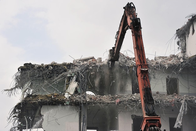 Démolition d'un ancien bâtiment - la destruction d'un bâtiment à l'aide d'un manipulateur de grue