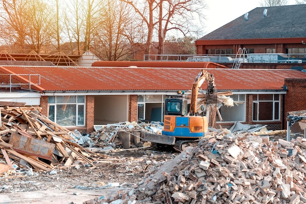 Démolition d'un bâtiment Une excavatrice casse une vieille maison Faire de la place pour la construction d'une nouvelle maison