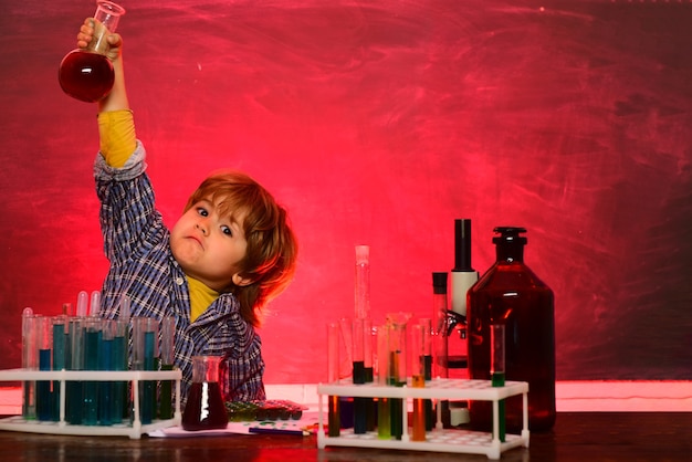 Une démonstration de chimie. Joyeux petit garçon souriant s'amusant contre le mur bleu. École