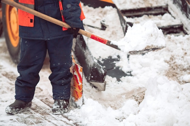 Déneigement dans la ville. Le travailleur aide à pelleter le chasse-neige.