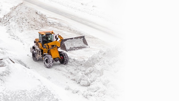 Déneigement. Le tracteur ouvre la voie après de fortes chutes de neige. Un grand tracteur orange enlève la neige