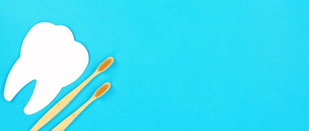 Dent blanche et brosse à dents en bois sur fond bleu espace de copie de bannière de concept de soins dentaires