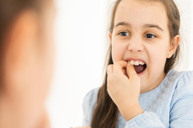 Une dent de lait lâche tombe chez une petite fille avec la bouche ouverte.