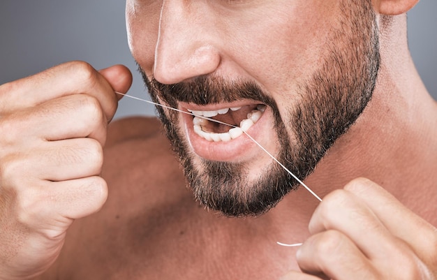 Dent de soie dentaire et homme en studio pour la beauté soins corporels sains et hygiène sur fond