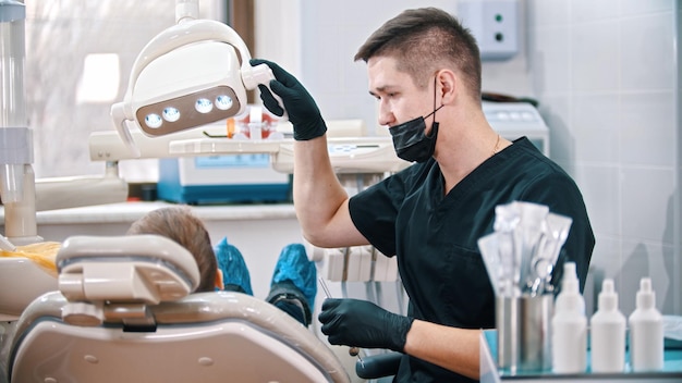 Un dentiste abaisse la lampe pour examiner la bouche d'un petit garçon