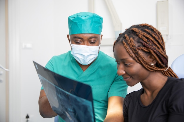 Un dentiste africain montre les radiographies à son patient lors d'une visite