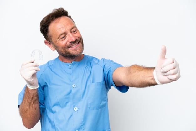 Dentiste d'âge moyen homme tenant envisageant isolé sur fond blanc donnant un geste du pouce levé
