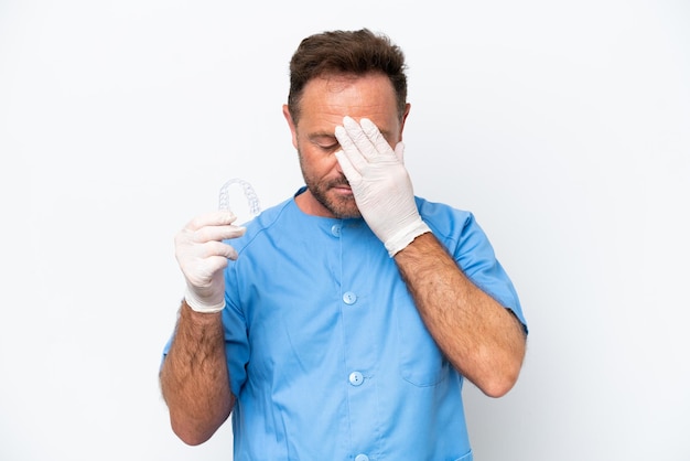 Dentiste d'âge moyen homme tenant envisageant isolé sur fond blanc avec une expression fatiguée et malade