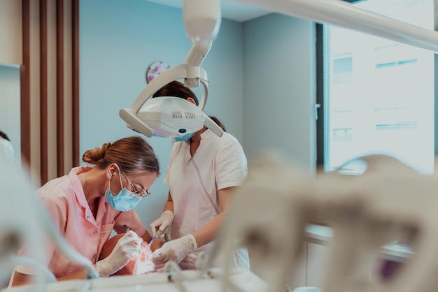 Un dentiste avec l'aide d'un collègue effectue une opération sur la mâchoire d'un patient âgé dans une clinique dentaire moderne. Photo de haute qualité