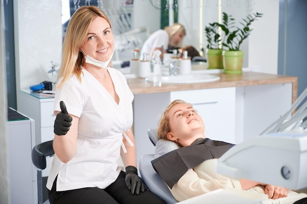 Dentiste Assis à Côté Du Patient Et Donnant Les Pouces Vers Le Haut