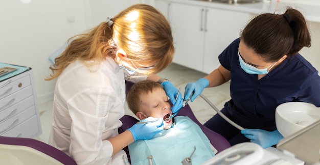 Dentiste et assistant examinant la bouche d'un enfant avec un instrument d'équipement de dentisterie Traitement des dents