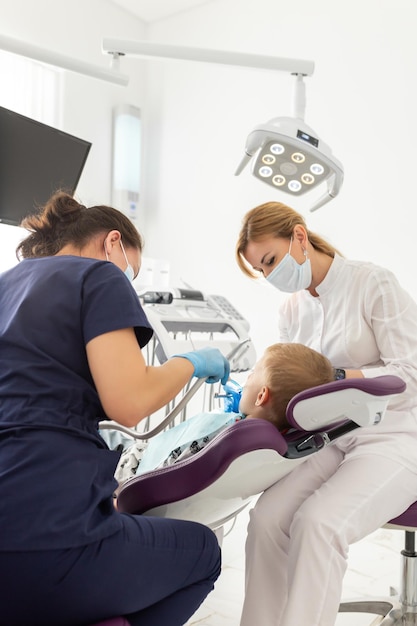 Dentiste et assistant examinant la bouche d'un enfant avec un instrument d'équipement de dentisterie Traitement des dents