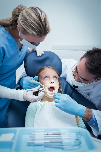 Dentiste avec assistant examinant les dents des filles