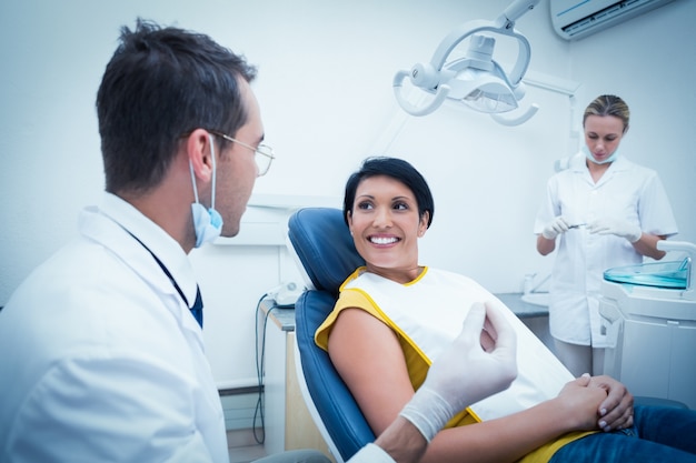 Dentiste et assistant avec une patiente souriante