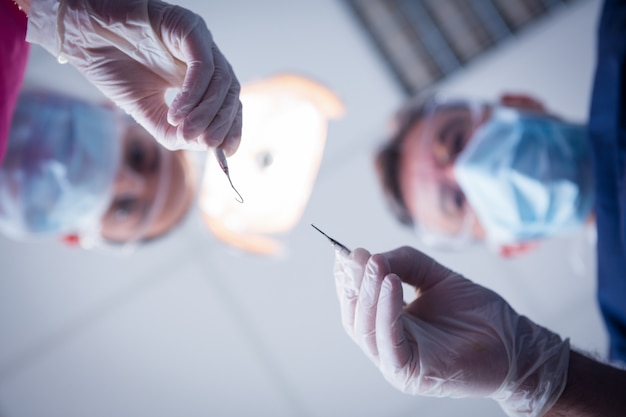 Dentiste et assistant se penchant sur le patient avec des outils