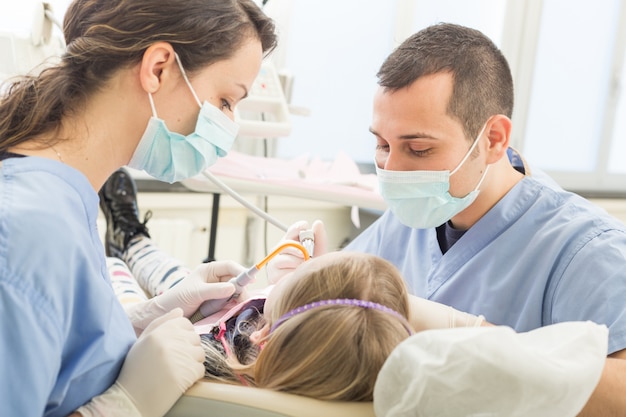 Dentiste et assistante dentaire examinant les dents d&#39;une jeune fille