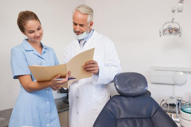 Photo dentiste et assistante examinant un dossier ensemble