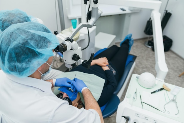 Un dentiste au microscope utilisé par un médecin traite un patient dans un cabinet dentaire moderne.