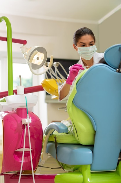 Dentiste aux cheveux foncés sérieux concentré appliquant des instruments dentaires