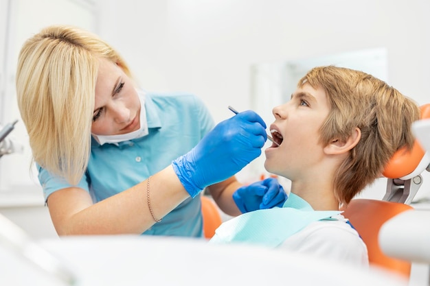 Dentiste blonde mignonne examinant les jeunes