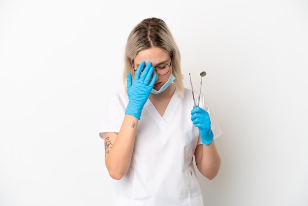 Dentiste caucasien femme tenant des outils isolés sur fond blanc avec une expression fatiguée et malade