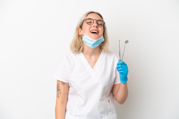 Dentiste caucasien femme tenant des outils isolés sur fond blanc en riant