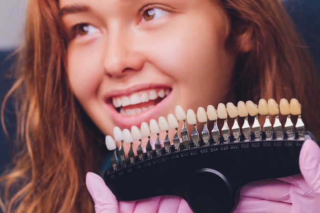 Le dentiste compare la teinte des dents du patient avec des échantillons pour le traitement de blanchiment.