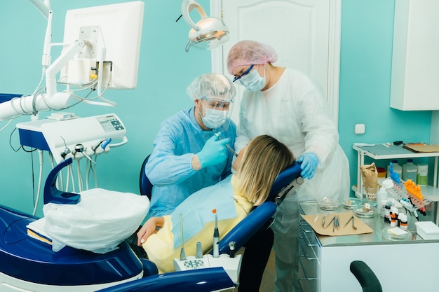 Un dentiste dans un masque de protection des analgésiques de la colite dans le cabinet dentaire avec un assistant.