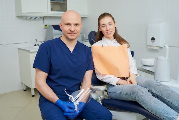 dentiste dans un uniforme et des gants médicaux jetables avec un patient dans un cabinet de dentiste