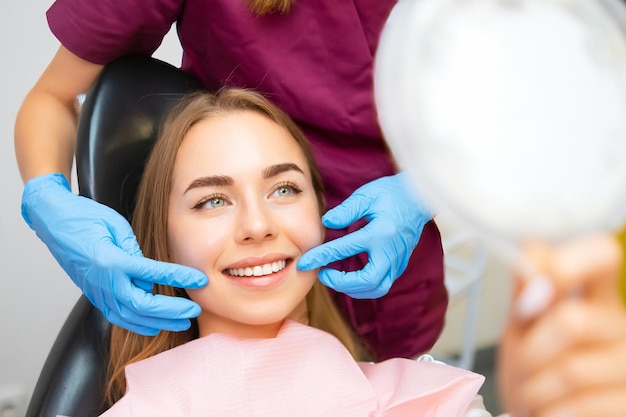 Le dentiste démontre le sourire parfait du patient après l'implantation de revêtements dentaires ou de dents