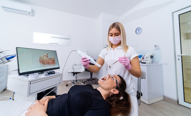 Le dentiste détient des instruments médicaux spécifiques pour le blanchiment des dents. Soins bucco-dentaires. Patient en chaise de stomatologie.