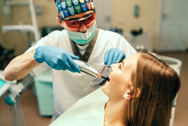 Dentiste effectue un traitement de la jeune fille avec des appareils dentaires dans un cabinet dentaire.