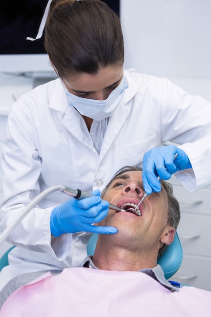 Dentiste examinant la bouche de l'homme senior à la clinique médicale