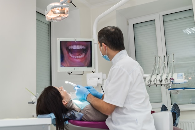 Dentiste examinant les dents du patient avec une caméra intra-orale