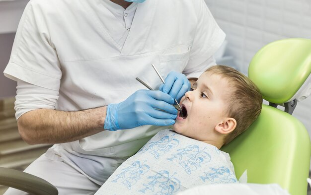 Dentiste examinant les dents du petit garçon à la clinique Problème dentaire